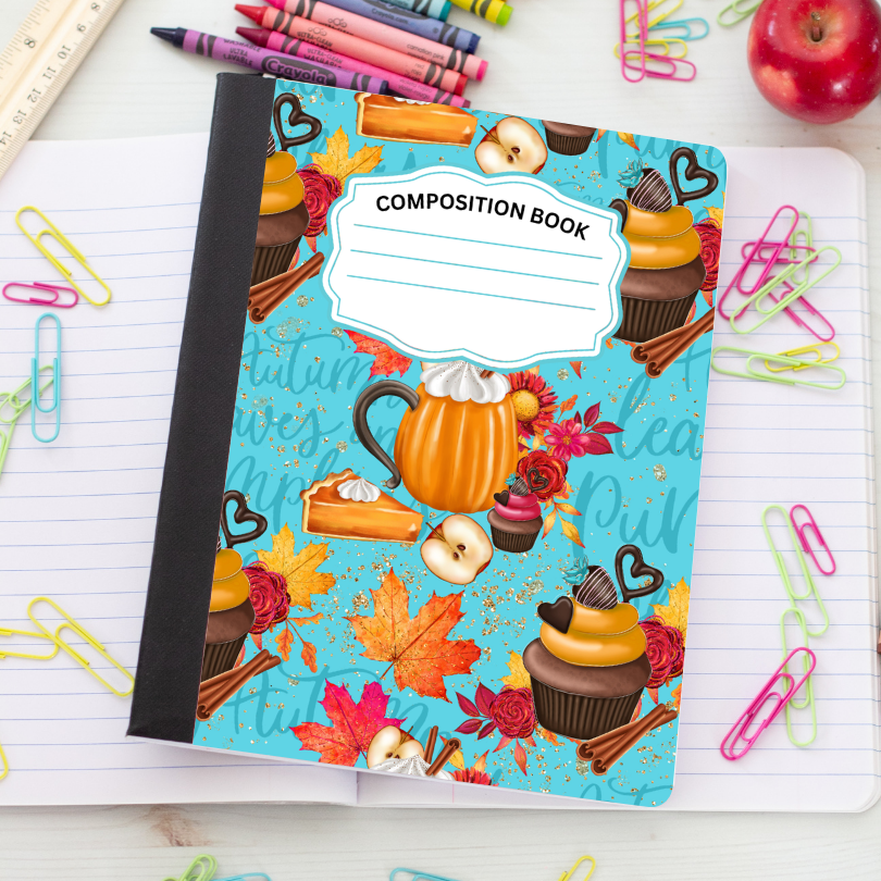 A composition notebook with a fall-themed cover featuring cupcakes, an orange pumpkin mug, autumn leaves, and the words 'Fruity Loops' and 'Creative Pith'. The notebook is placed on an open lined notebook surrounded by school supplies like paper clips, pencils, and an apple.
