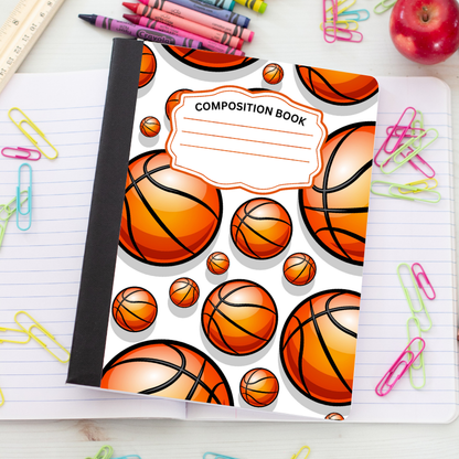 A composition book with a basketball pattern cover, placed on top of an open lined notebook surrounded by colorful paperclips, crayons, a ruler, and an apple.