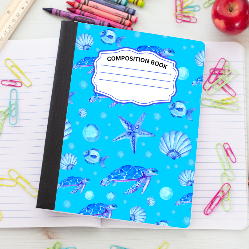 A blue composition book with an underwater sea turtle and starfish pattern, styled on an open lined notebook surrounded by colorful paperclips, crayons, a ruler, and an apple.