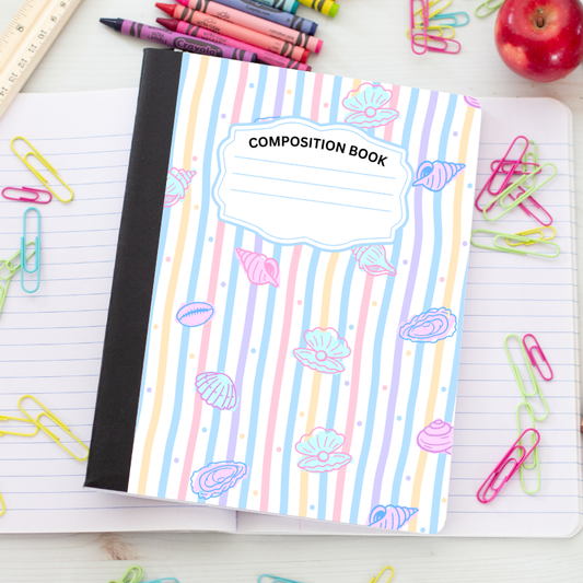 A pastel striped composition notebook with seashell illustrations and a lined page underneath, surrounded by school supplies like paper clips, crayons, a ruler, and an apple on a light wood surface.